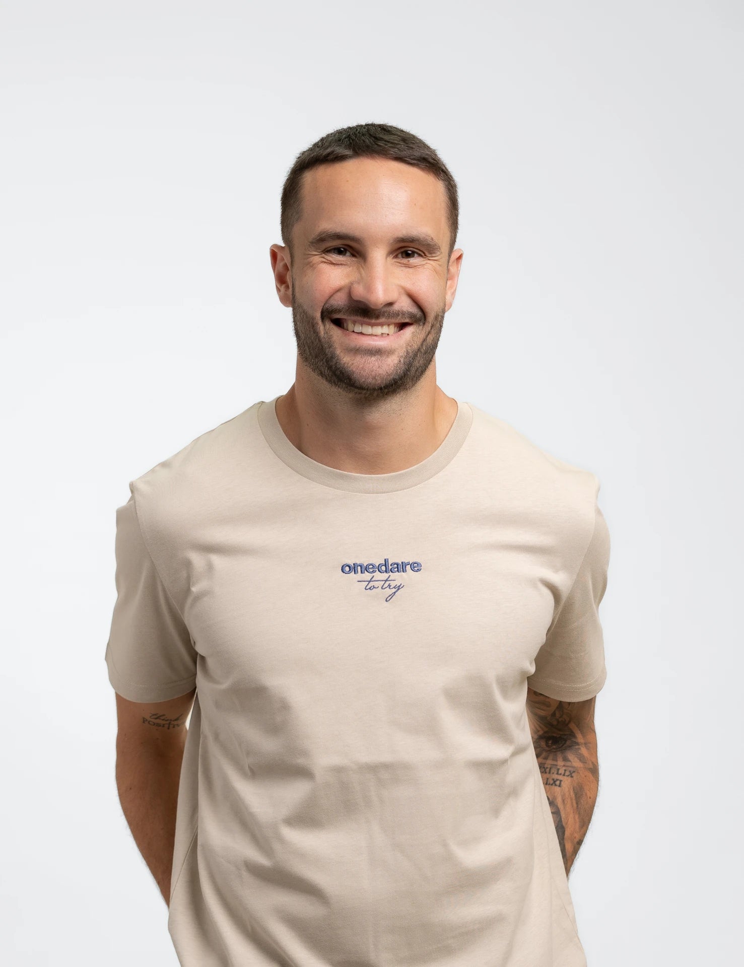 Sandfarbenes classic Bio-Baumwolle T-Shirt mit blauem, onedare totry Stick mittig auf der Brust.